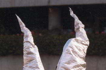 two performers inside two tall, slightly crushed silver cones