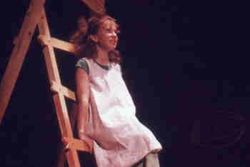 girl sits halfway up a red wooden ladder